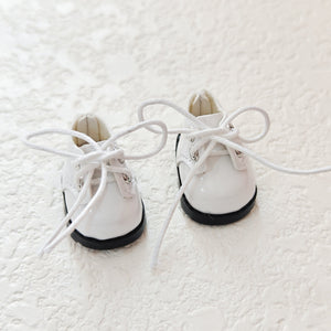 A pair of lace up white leather shoes